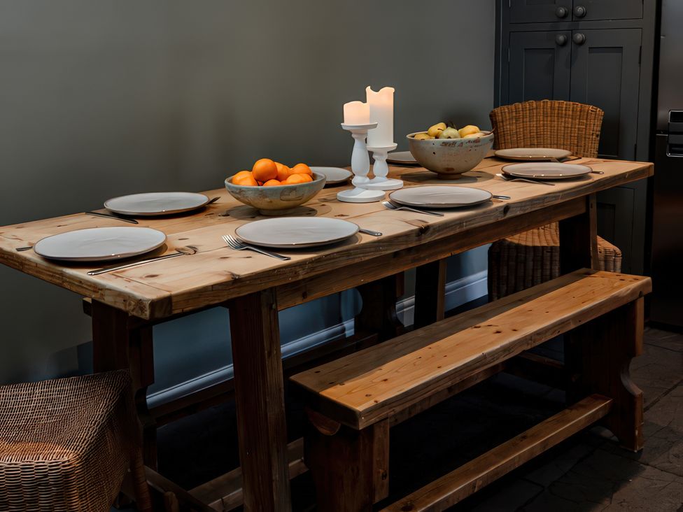A dining room with a wooden table set for a meal at Bridge End Cottage Stainforth