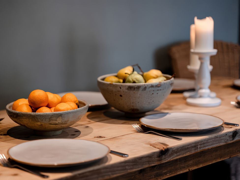 A dining table with fruit bowls and plates at Bridge End Cottage Stainforth