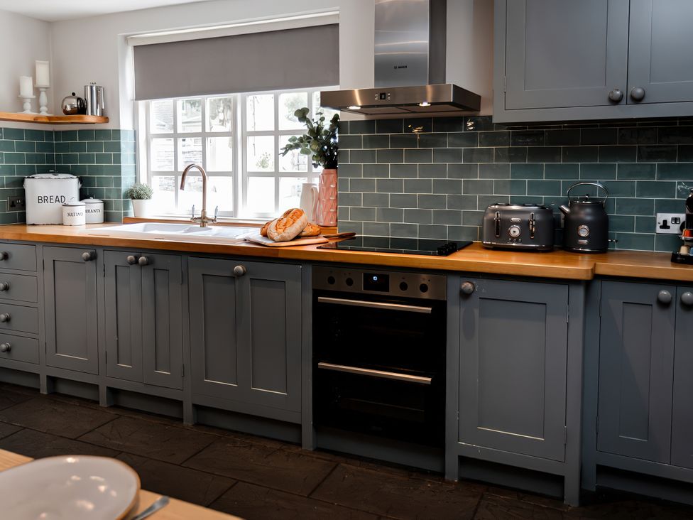 A kitchen with cabinets, sink, oven, and appliances at Bridge End Cottage in Stainforth