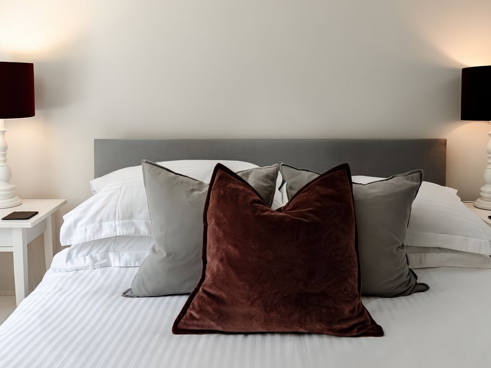 A bedroom with a bed and pillows near a lamp at Bridge End Cottage Stainforth