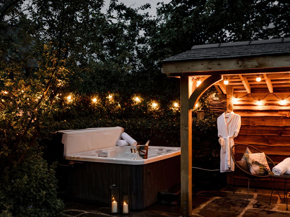 A hot tub with towels and bathrobe in a garden at Bridge End Cottage Stainforth