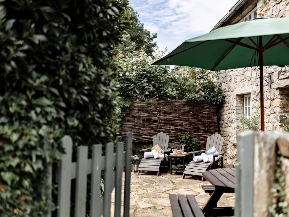 A garden with deck chairs and a table at Bridge End Cottage in Stainforth