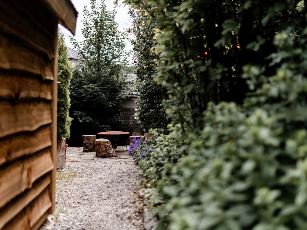 A garden with a stone pathway and a stump table at Bridge End Cottage in Stainforth