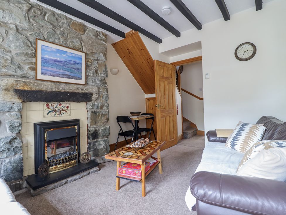 A living room with a fireplace and stairs at Cae Tanws Bach in Dolgellau