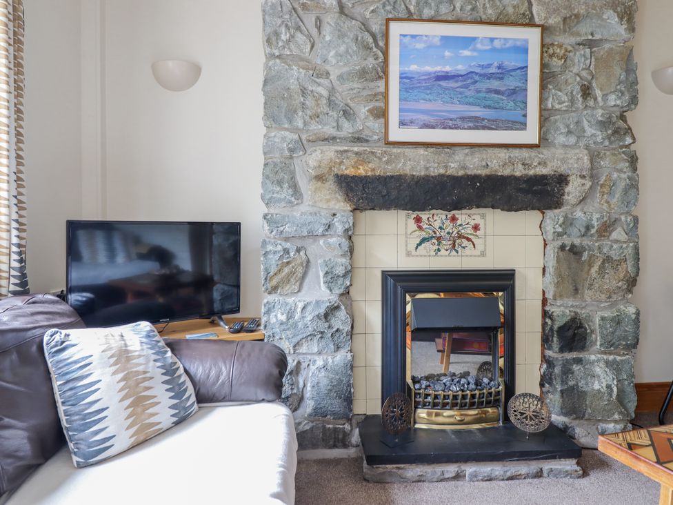A living room with a stone fireplace and sofa at Cae Tanws Bach in Dolgellau