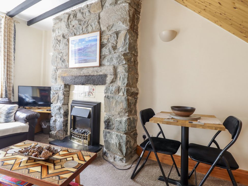 A living room with a stone fireplace and a table at Cae Tanws Bach Dolgellau