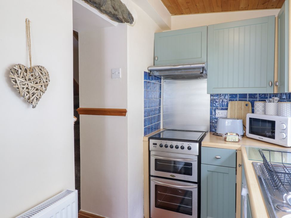 A kitchen with an oven and microwave at Cae Tanws Bach in Dolgellau