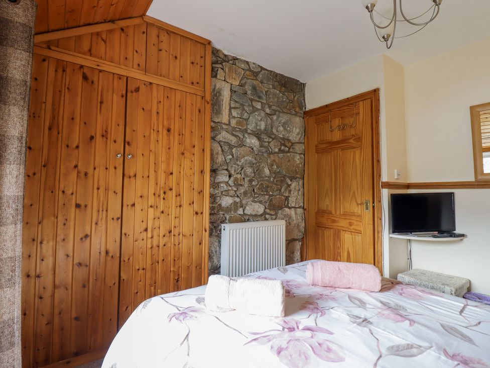 A bedroom with wooden wardrobe and television at Cae Tanws Bach in Dolgellau