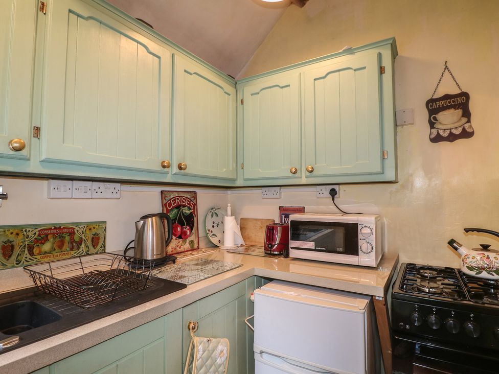 A kitchen with green cabinets and appliances at 40 Water Lane Matlock