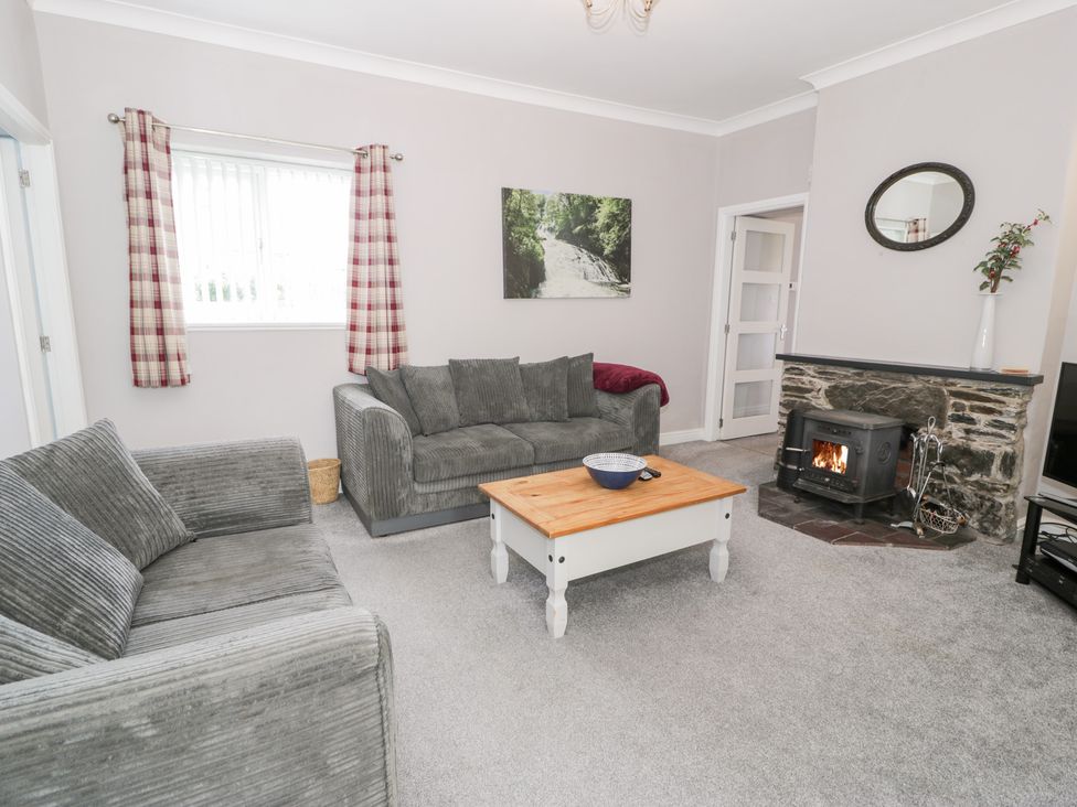 A living room with a sofa, armchair, coffee table, and fireplace at Dyffryn Bach in Glan-yr-afon near Corwen