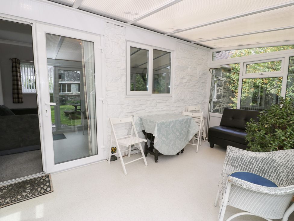 A conservatory with a table and chairs at Dyffryn Bach in Glan-yr-afon near Corwen