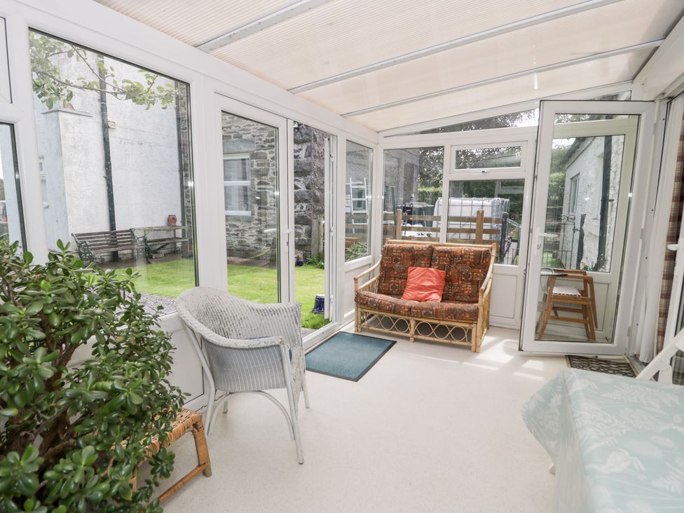 A conservatory with seating and plants at Dyffryn Bach in Glan-yr-afon near Corwen
