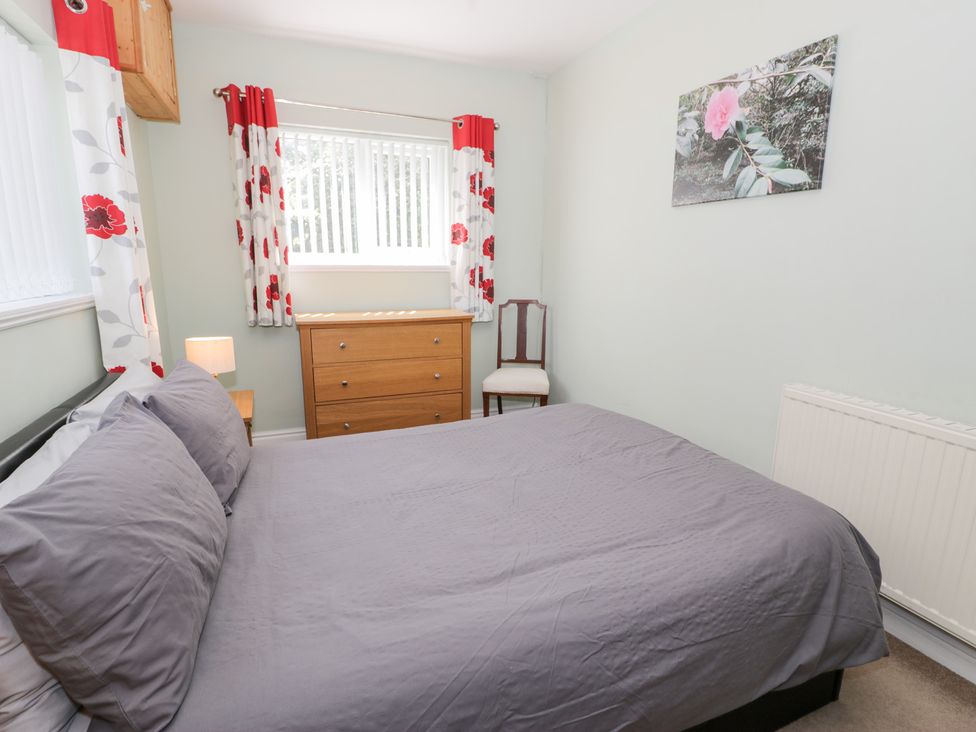 A bedroom with a bed, dresser, and chair at Dyffryn Bach in Glan-yr-afon near Corwen