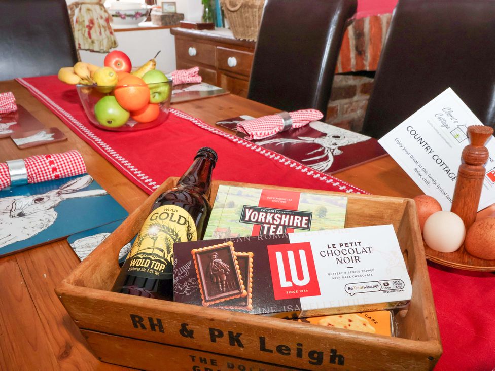 A dining table with fruit, biscuits, tea, and beer at Clara's Cottage in West Lutton near Malton