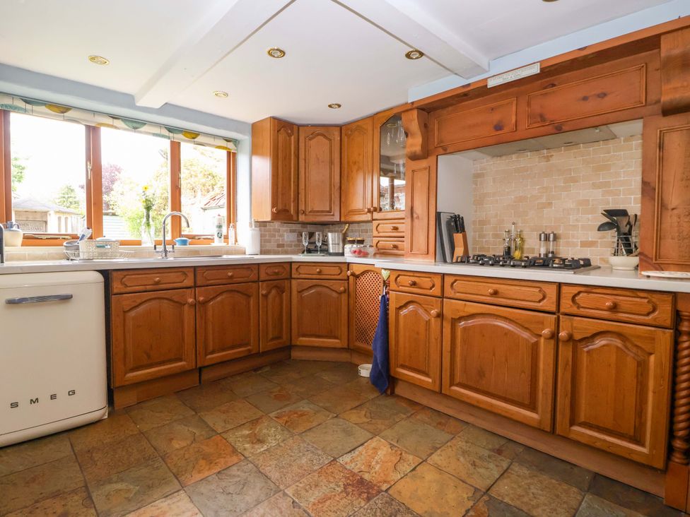 A kitchen with wooden cabinets and a stove at Clara's Cottage in West Lutton near Malton