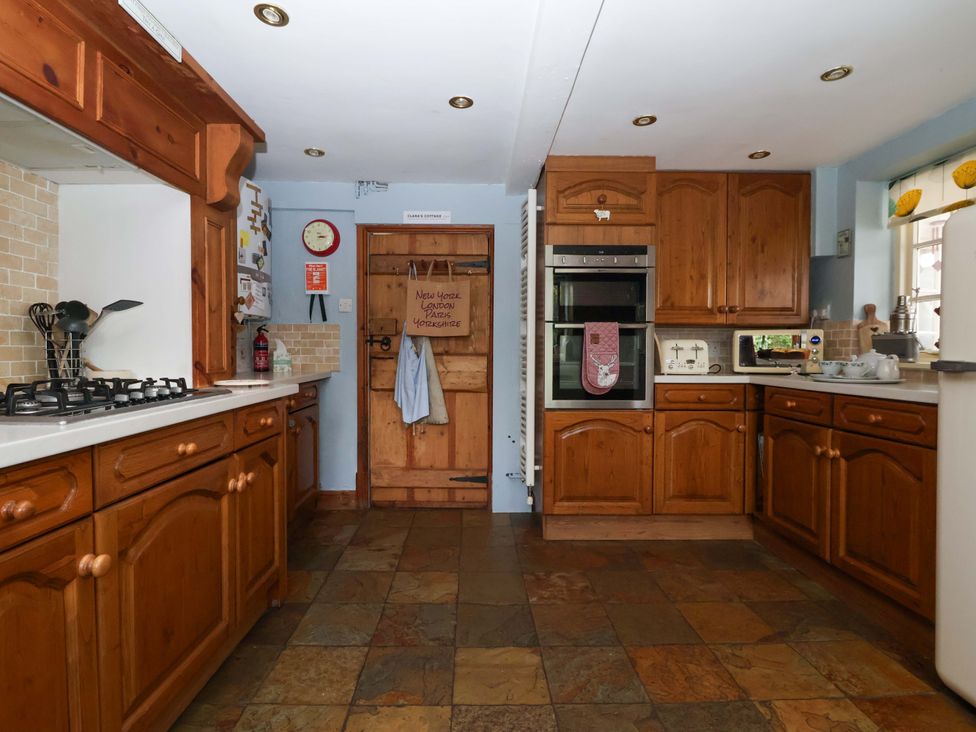 A kitchen with wooden cabinets and appliances at Clara's Cottage in West Lutton near Malton