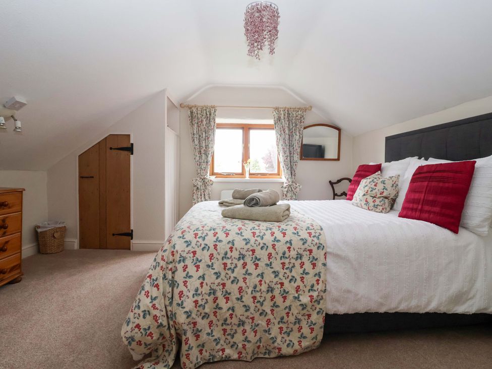 A bedroom with a bed and window at Clara's Cottage in West Lutton near Malton