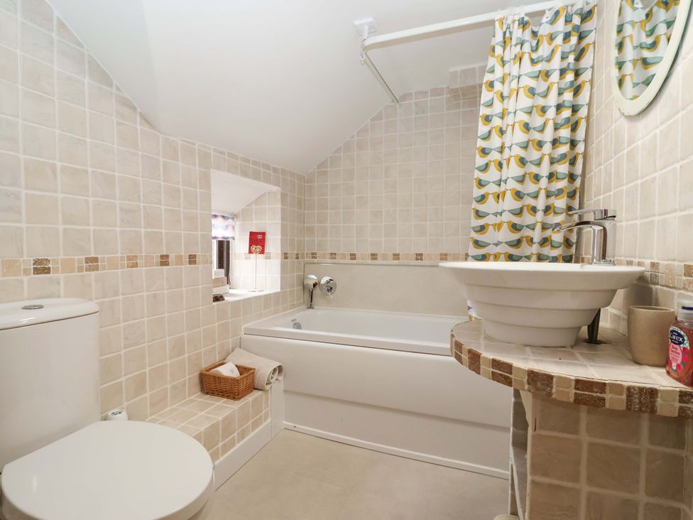 A bathroom with a toilet, bathtub, and sink at Clara's Cottage West Lutton near Malton
