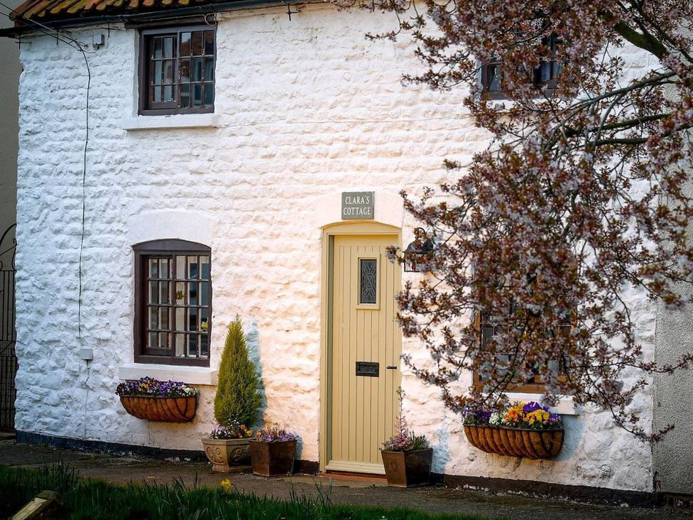 A cottage exterior with a door and flower pots at Clara's Cottage West Lutton near Malton