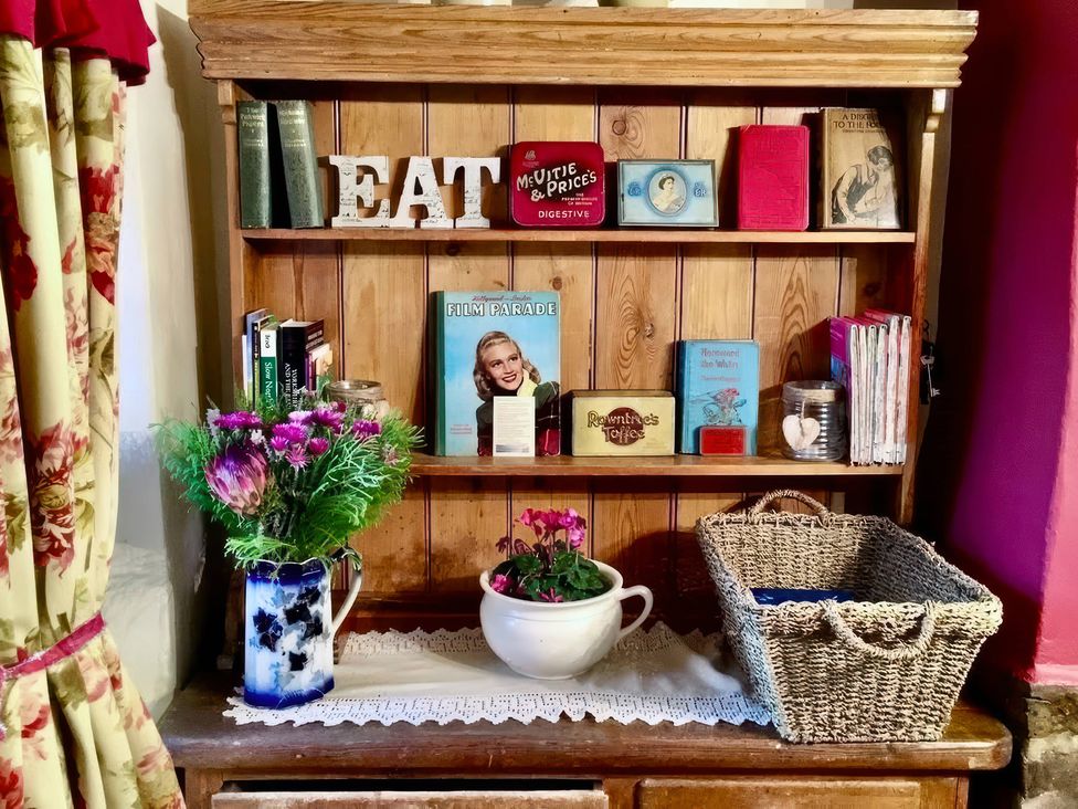 A shelf with books and a vase of flowers at Clara's Cottage West Lutton near Malton