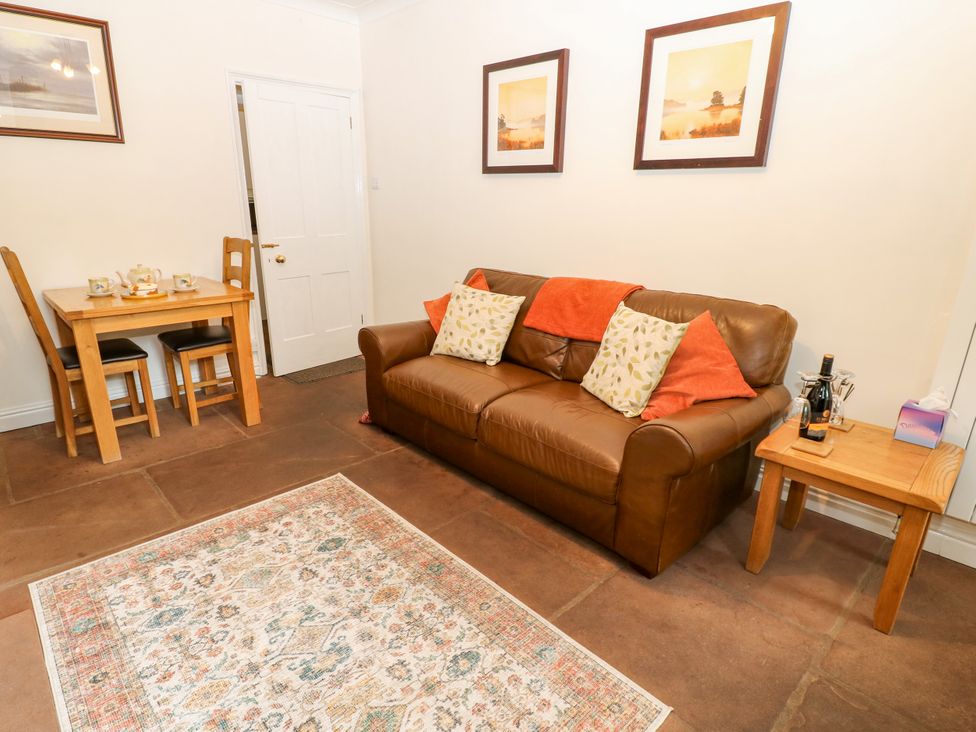 A living room with a sofa and dining area at 27 Bongate in Appleby-In-Westmorland