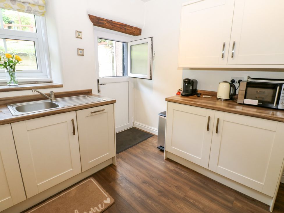 A kitchen featuring a sink, kettle, and microwave at 27 Bongate in Appleby-In-Westmorland