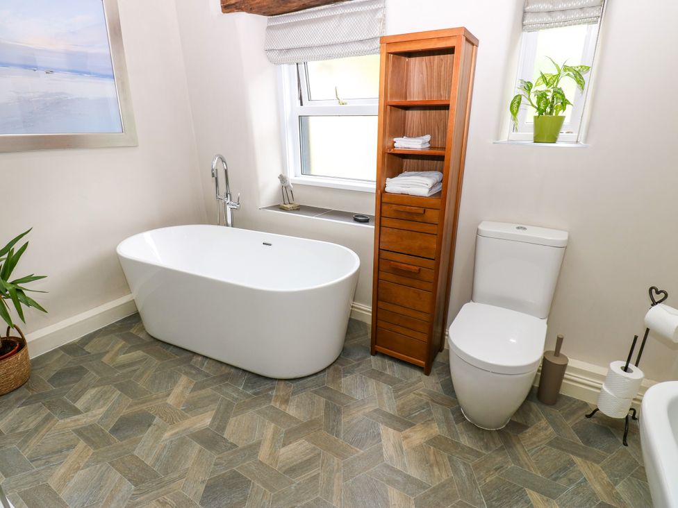 A bathroom with a bathtub, toilet, and shelf at 27 Bongate in Appleby-In-Westmorland
