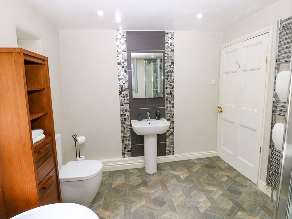 A bathroom with a sink, toilet, and wooden cabinet at 27 Bongate in Appleby-In-Westmorland