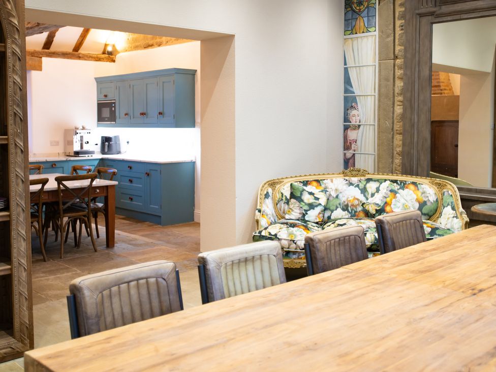 A dining room with a table and chairs leading to a kitchen at Wren Place Hall in Worsbrough