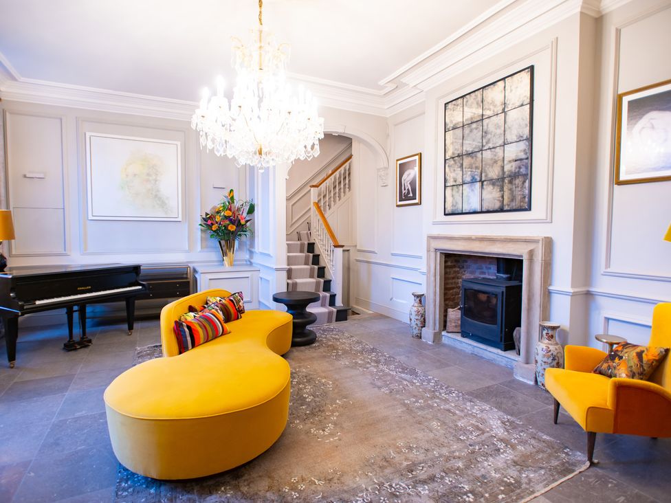 A living room with a piano and a yellow sofa at Wren Place Hall in Worsbrough
