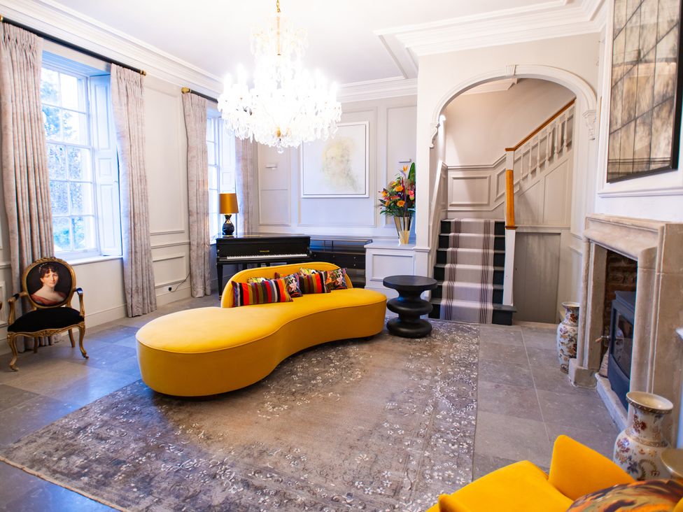 A living room with a yellow sofa and a piano at Wren Place Hall in Worsbrough