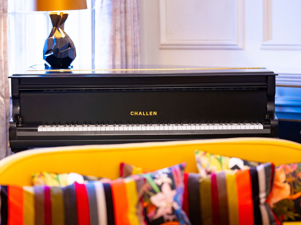 A piano next to a lamp and cushions in the living room at Wren Place Hall in Worsbrough