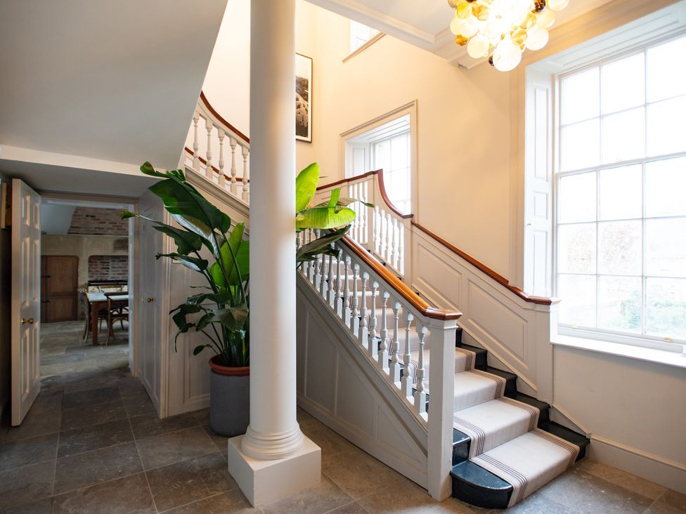 A hallway with stairs and a houseplant at Wren Place Hall in Worsbrough