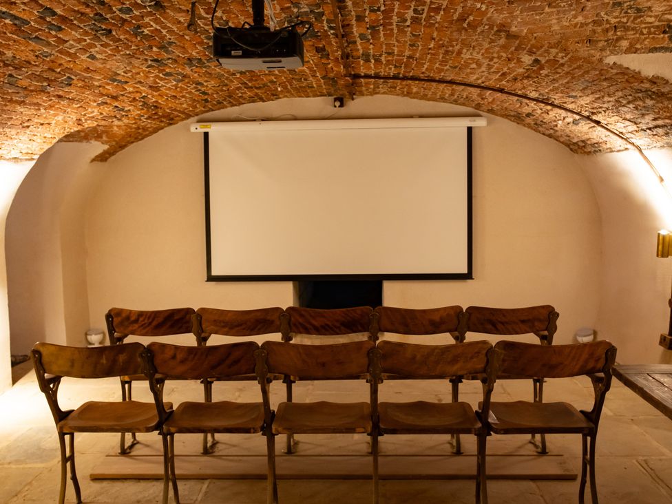 A cinema room with seating and a projection screen at Wren Place Hall Worsbrough
