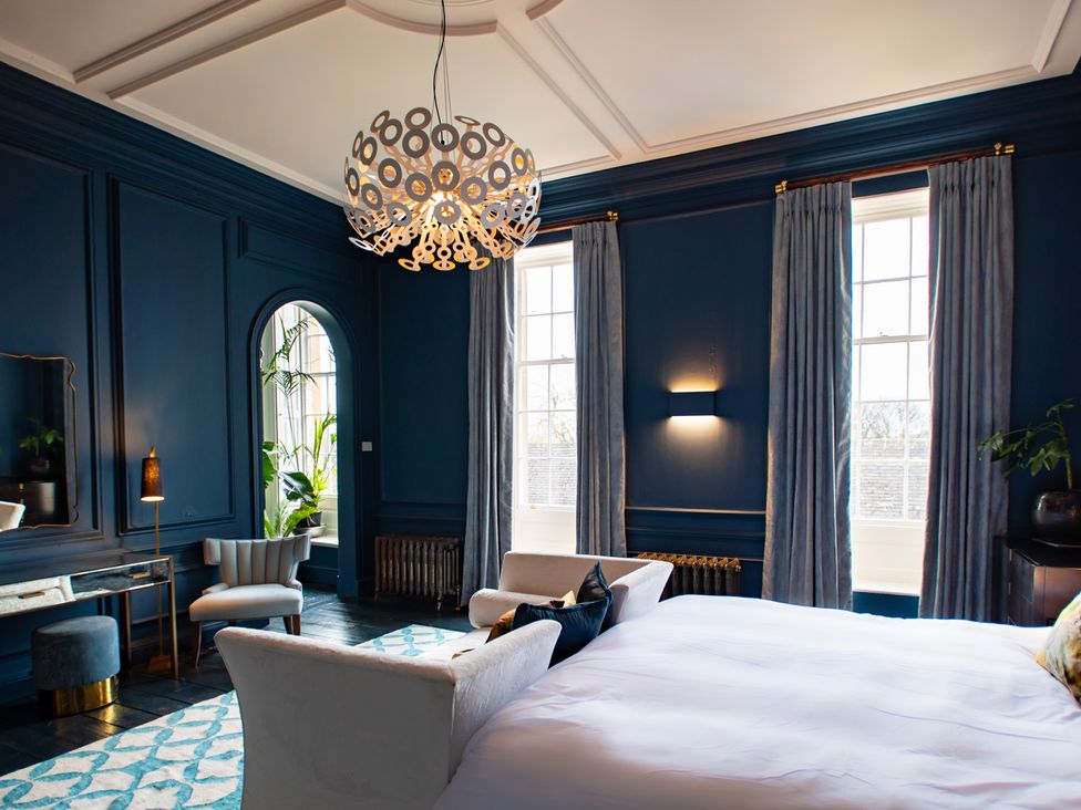 A bedroom with a bed and armchair at Wren Place Hall in Worsbrough