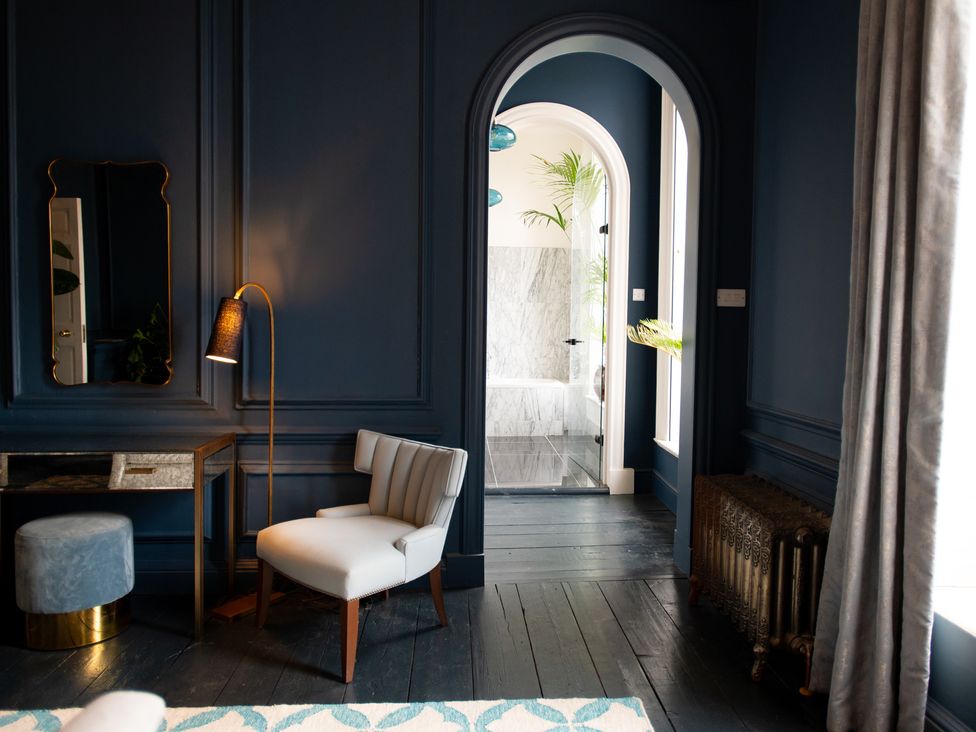 A living room with a chair and console table at Wren Place Hall in Worsbrough