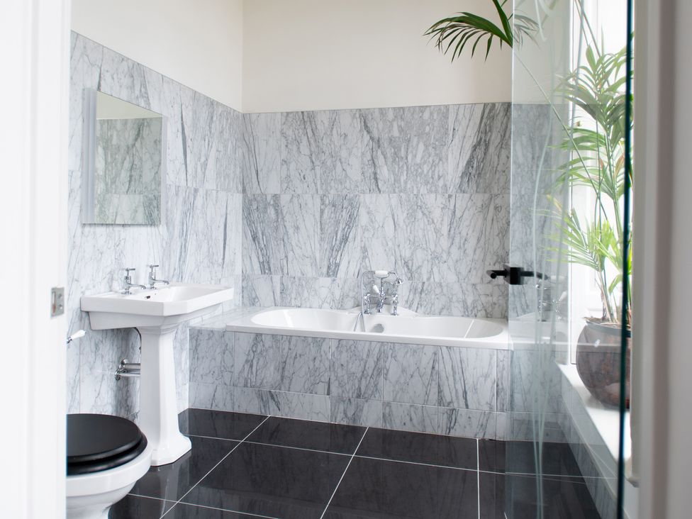 A bathroom with a bathtub, sink, and toilet at Wren Place Hall in Worsbrough
