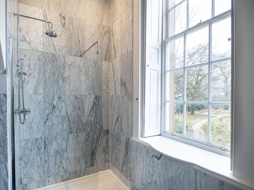 A shower with marble tiles and window at Wren Place Hall in Worsbrough
