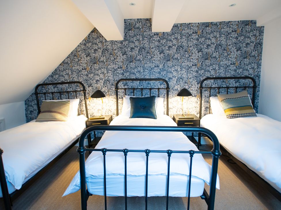 A bedroom with three beds and a patterned wall at Wren Place Hall in Worsbrough
