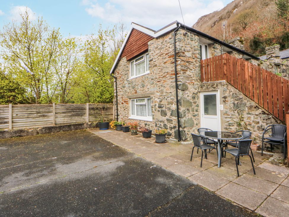An outdoor area with a stone building and seating at Ground Floor Apartment, Tremadog
