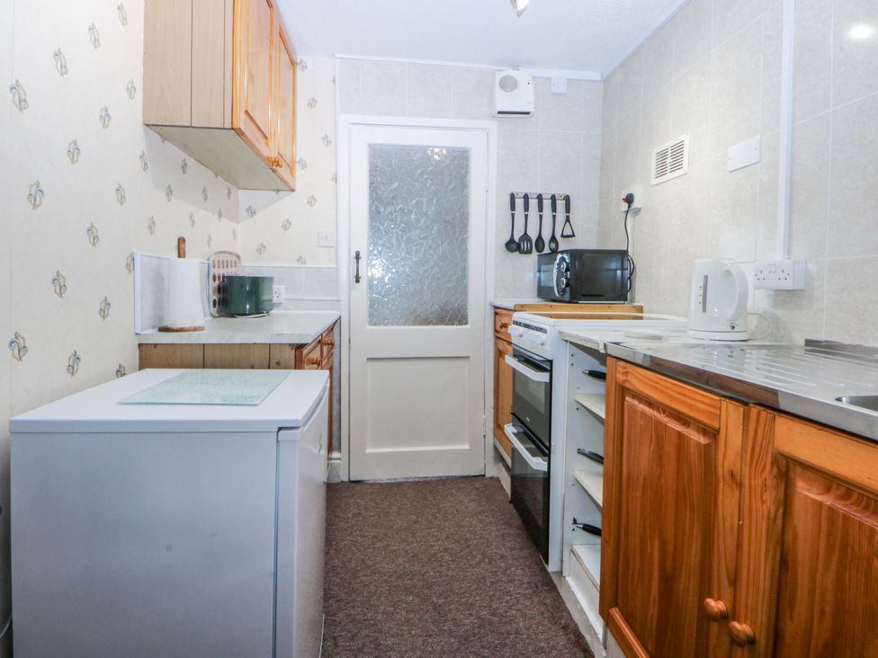 A kitchen with appliances and cabinetry at Ground Floor Apartment Tremadog