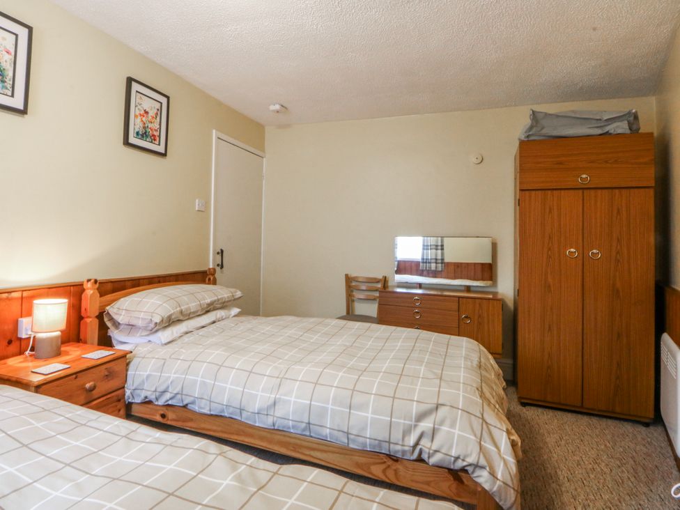 A bedroom with two beds and a wardrobe at Ground Floor Apartment Tremadog