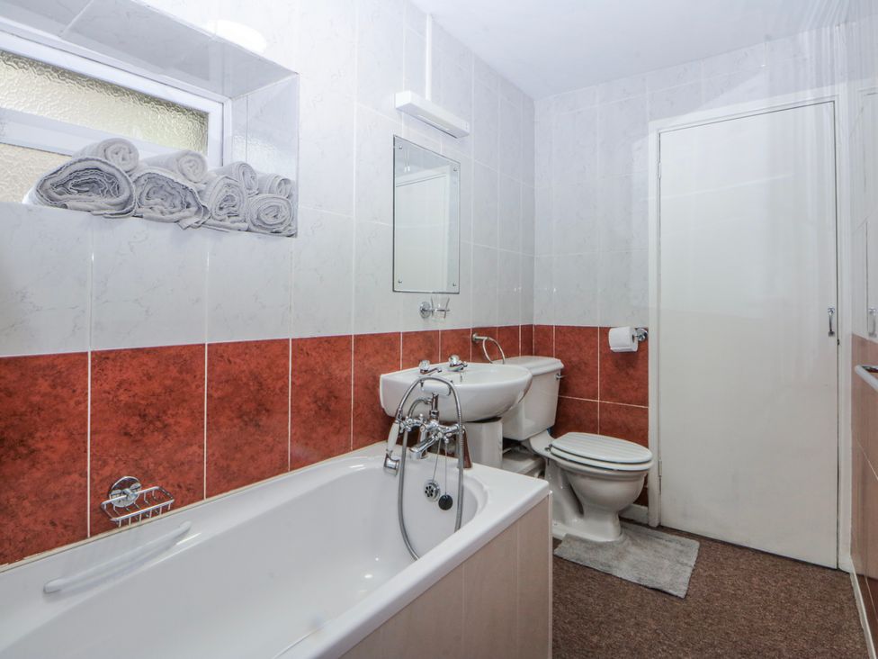 A bathroom with a bathtub, toilet, and sink at Ground Floor Apartment in Tremadog
