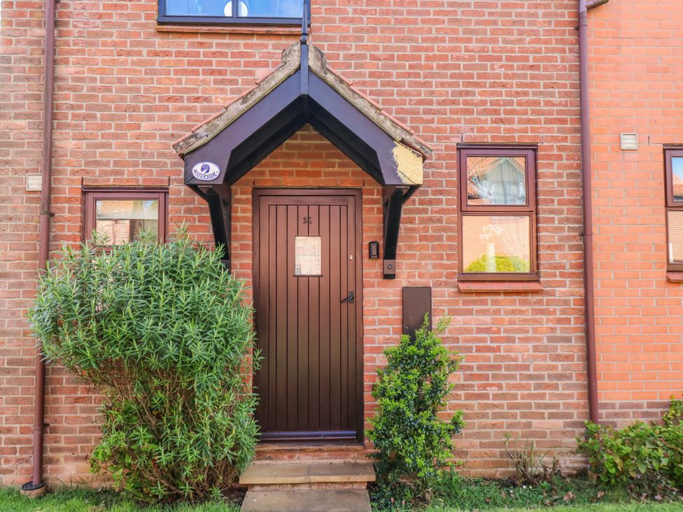 A front door with windows and bushes at Waterside Cottage in Whitby