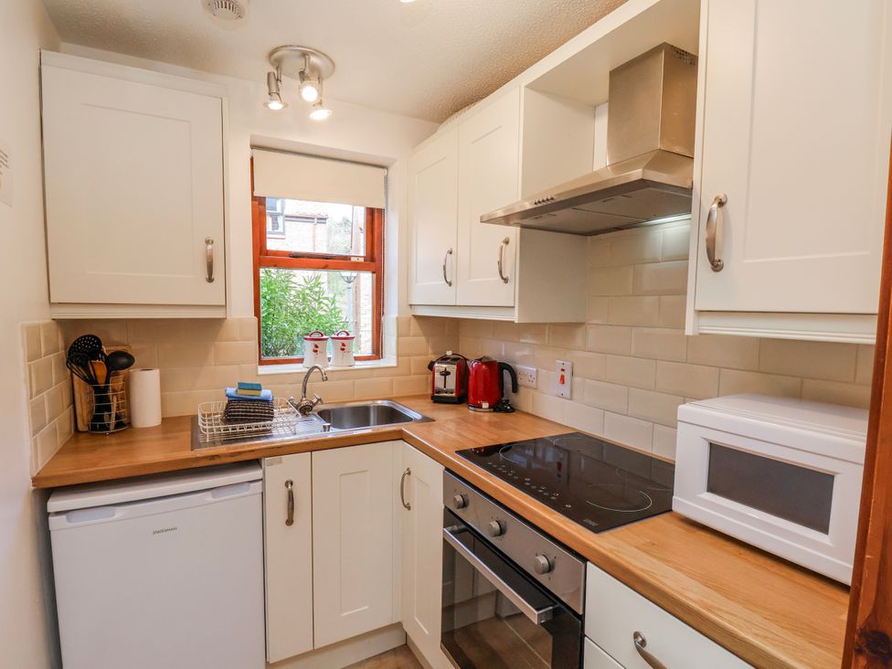 A kitchen with a sink, stove, microwave and refrigerator at Waterside Cottage in Whitby