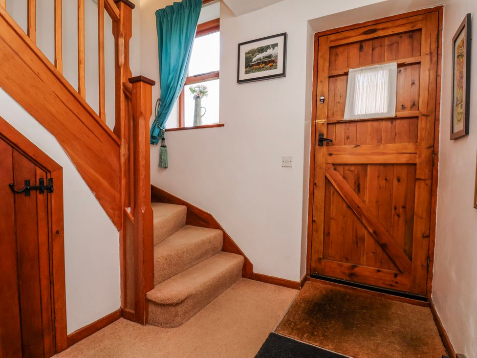 A hallway with stairs and a wooden door at Waterside Cottage Whitby