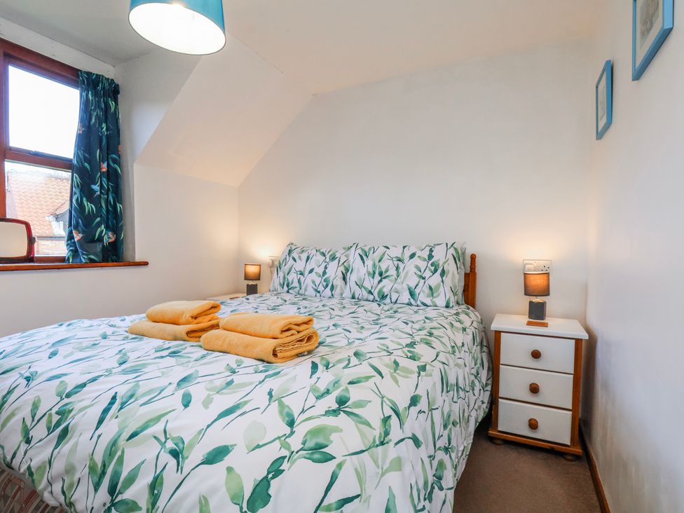 A bedroom with a bed and nightstand at Waterside Cottage in Whitby