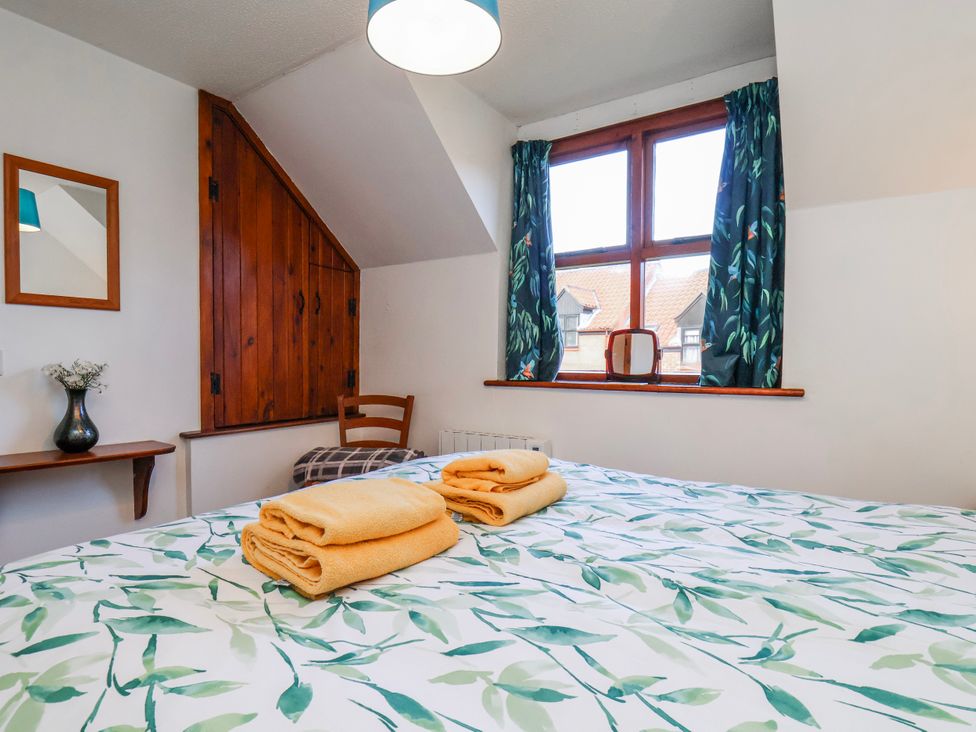 A bedroom with a bed, towels on it and a window at Waterside Cottage in Whitby