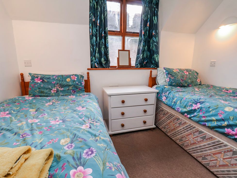 A bedroom with two beds and a white drawer at Waterside Cottage in Whitby