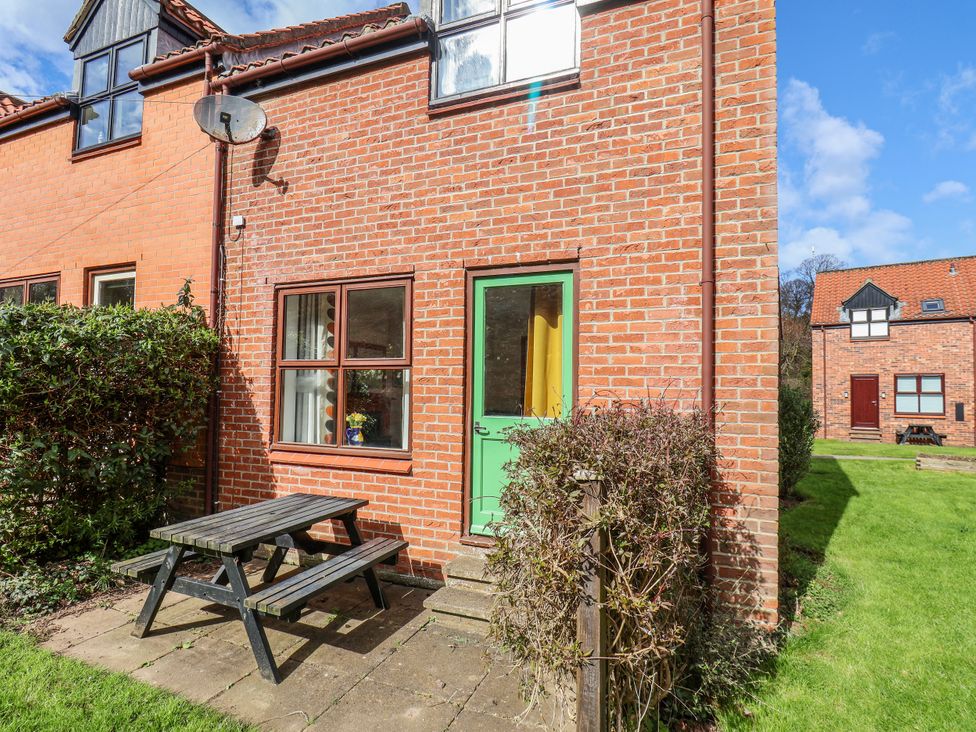 An outdoor view with a green door and table at Waterside Cottage in Whitby